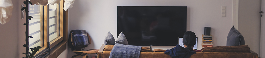 Coin télévision avec canapé et couple qui regarde la télévision.